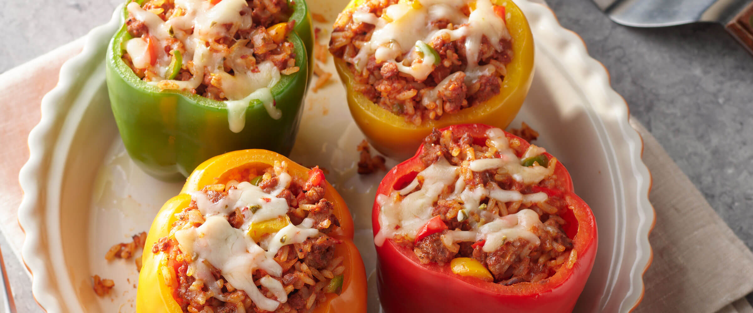 Meatloaf Stuffed Peppers in white dish topped with cheese