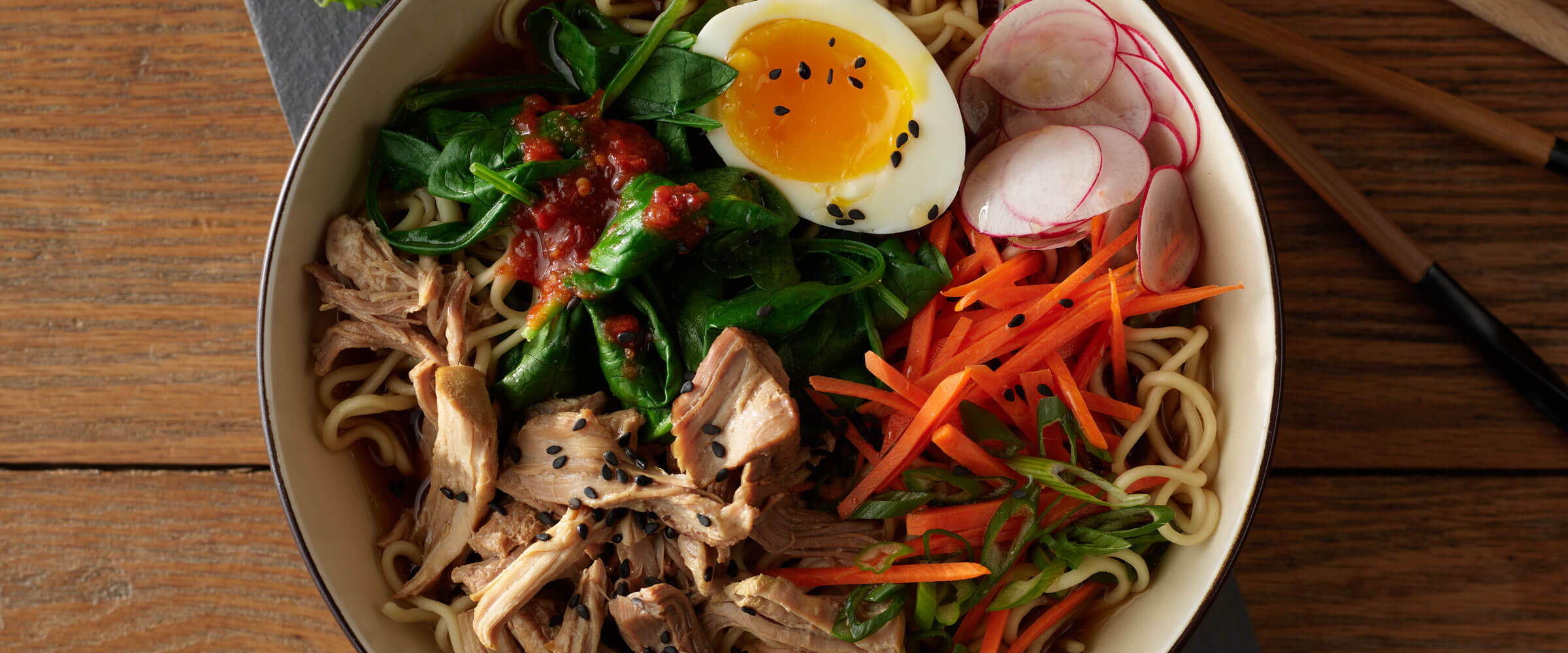 Pork Ramen Noodle Bowl topped with egg and vegetables