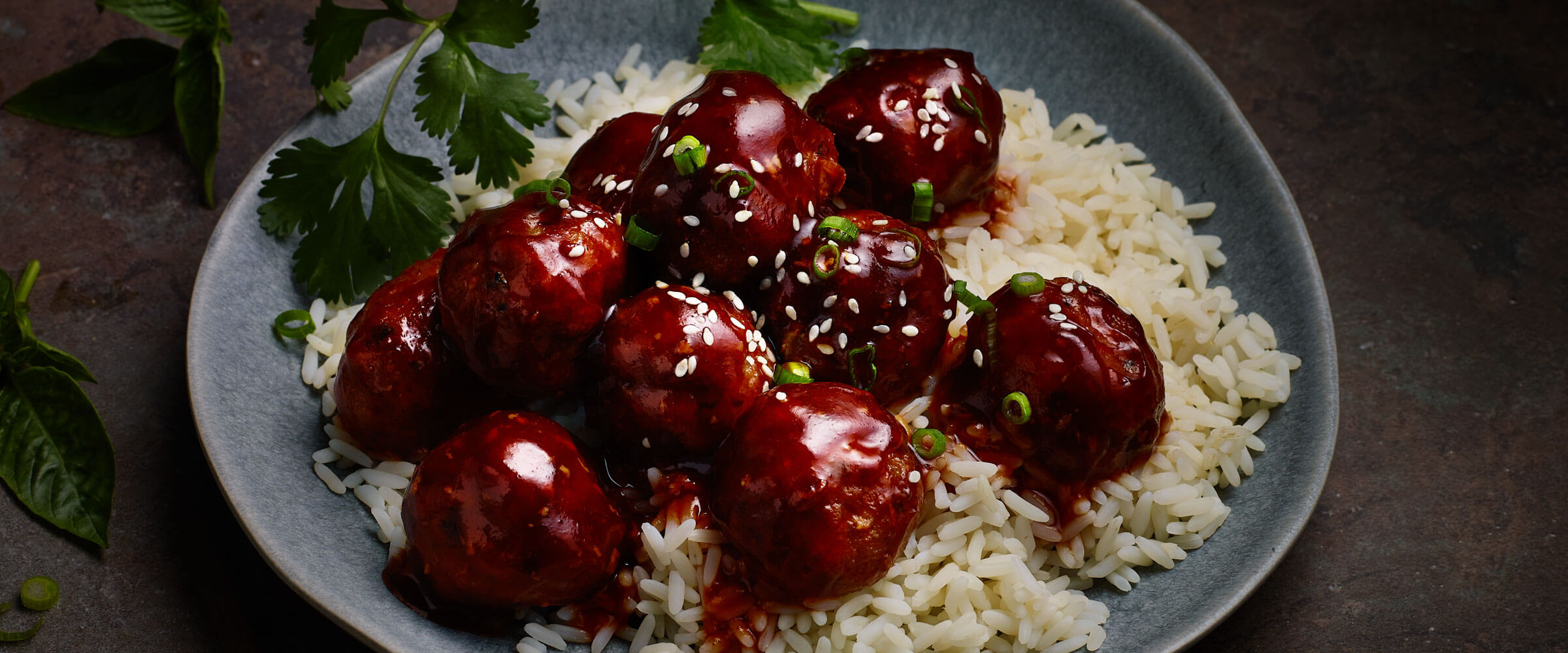 Easy Sweet and Spicy Meatballs over rice on blue plate with garnish