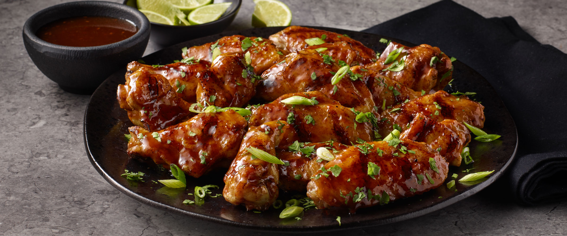 Grilled Korean BBQ Chicken Wings with sliced limes and bbq sauce