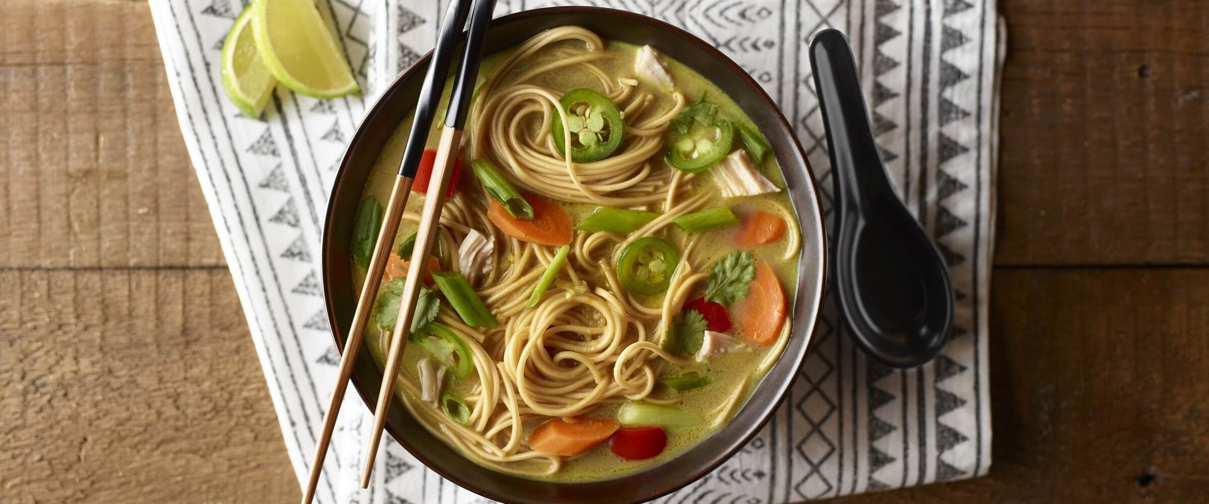 asian chicken noodle soup with jalapenos in black bowl with chopsticks