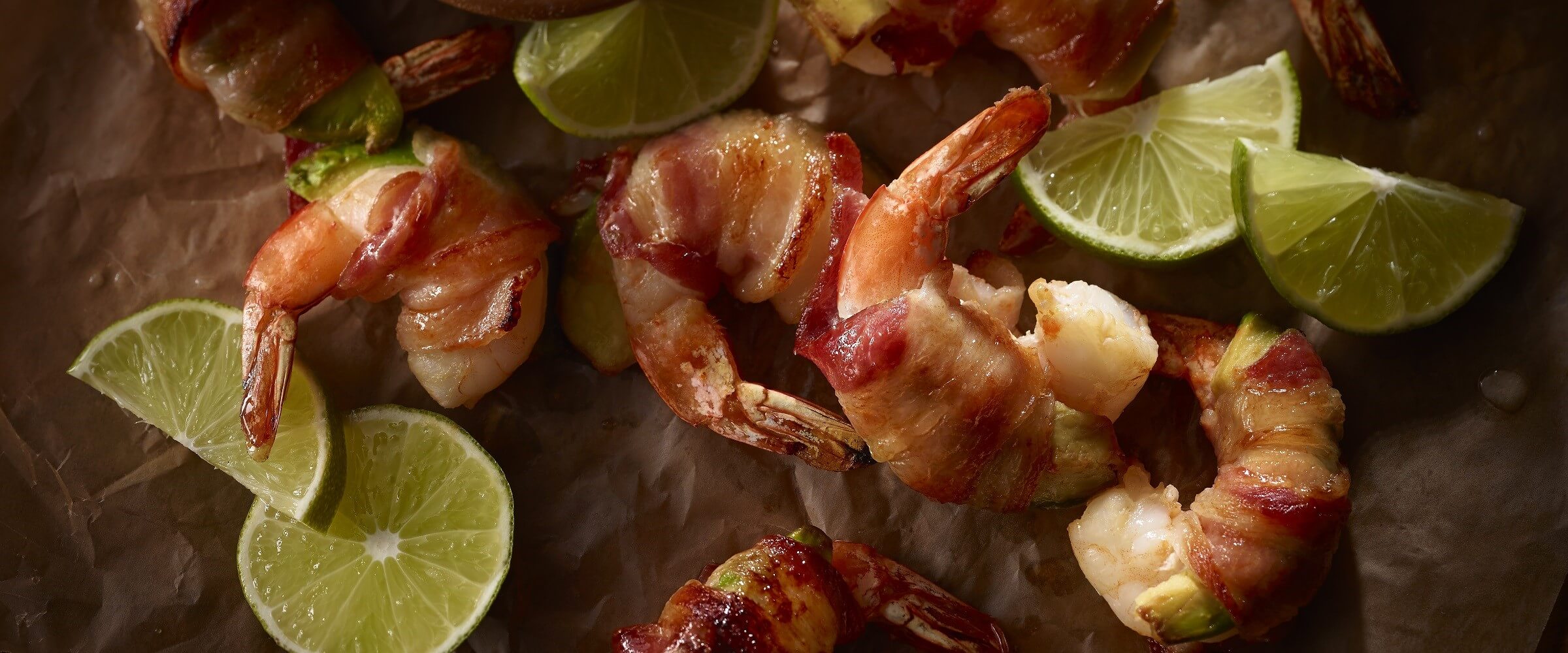 bacon wrapped shrimp and avocado with lime wedges