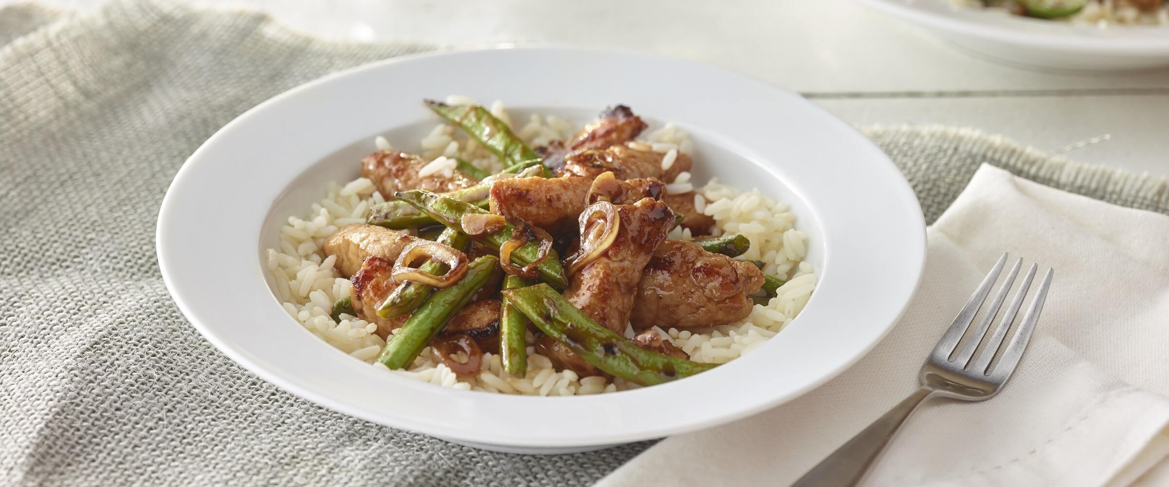 general tso’s pork and green beans over rice in white bowl