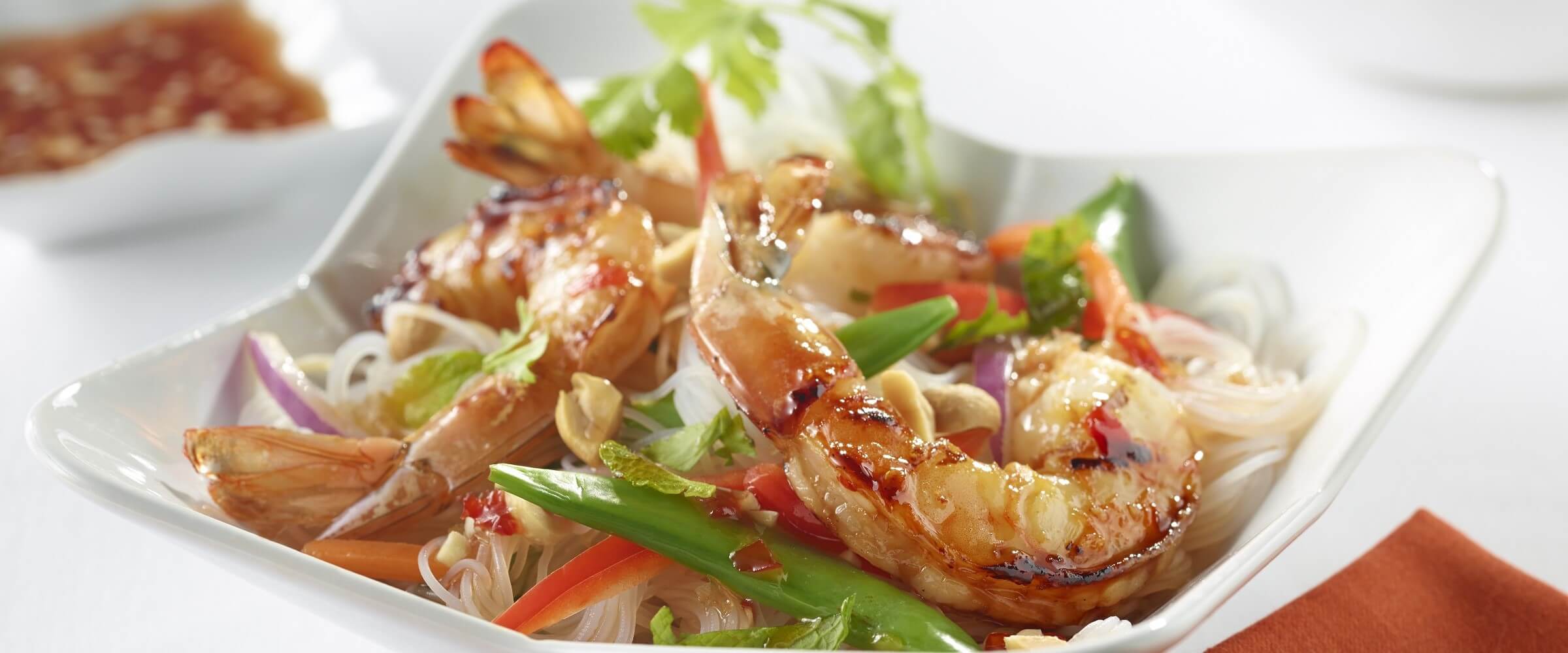 shrimp noodle salad in white bowl with garnish