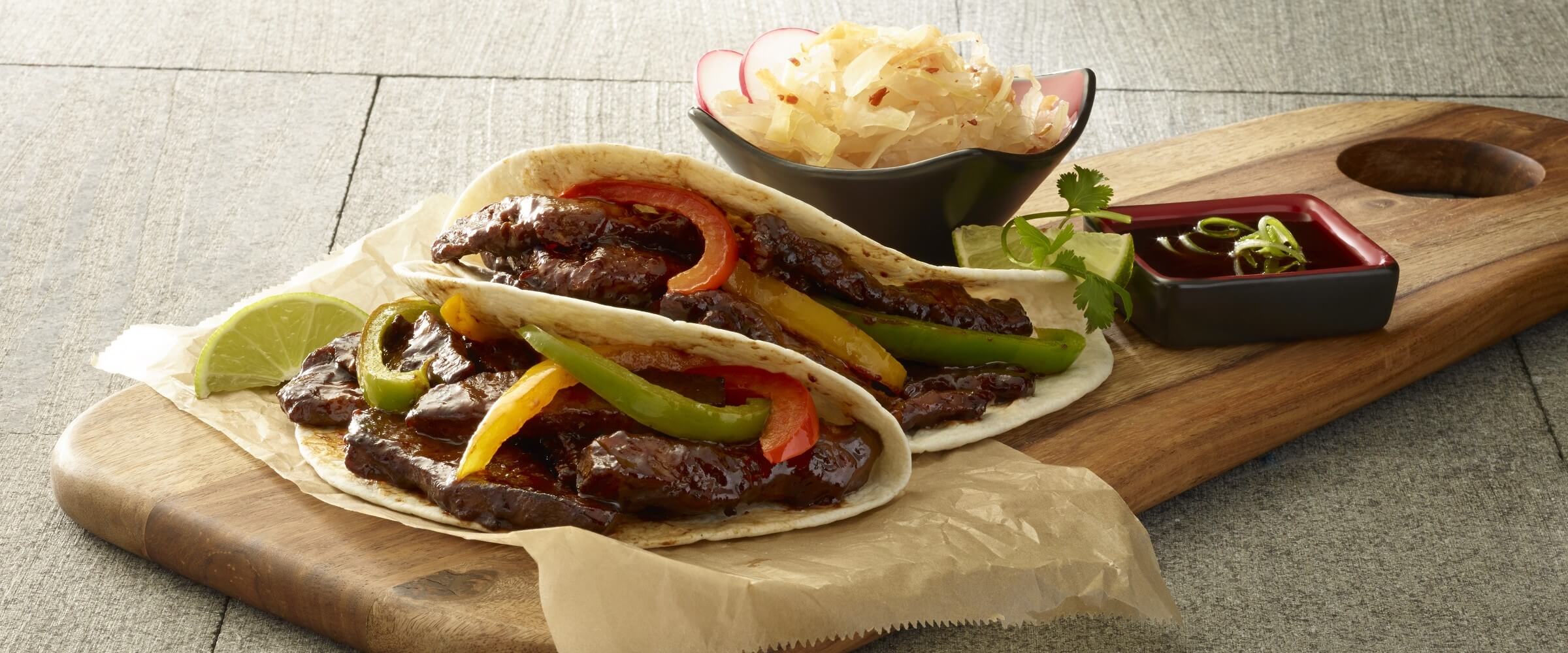 spicy korean street tacos with vegetables on wood platter with dipping sauce