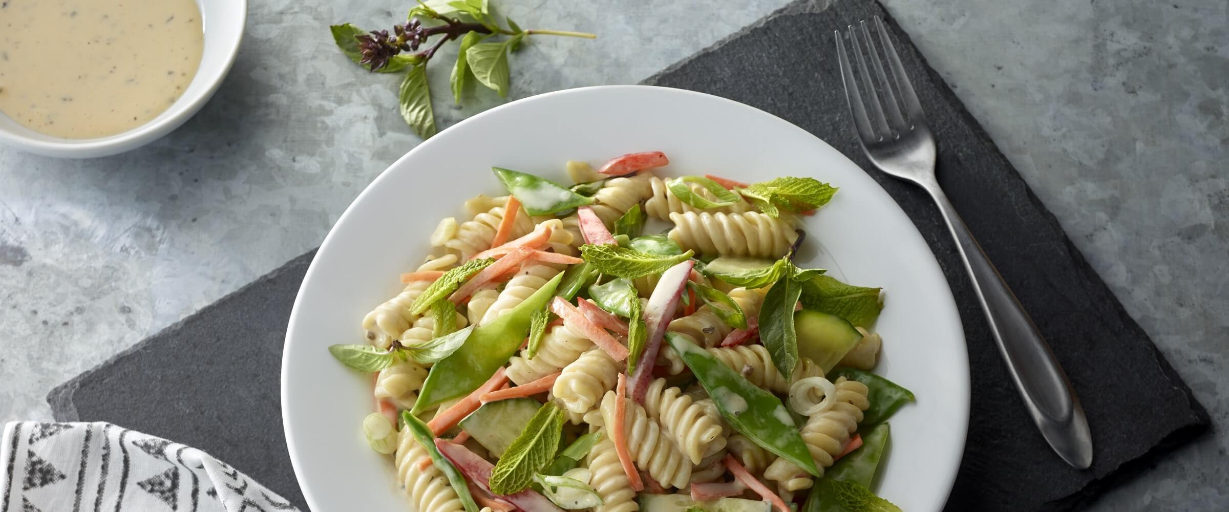 thai basil pasta salad in white bowl with fork