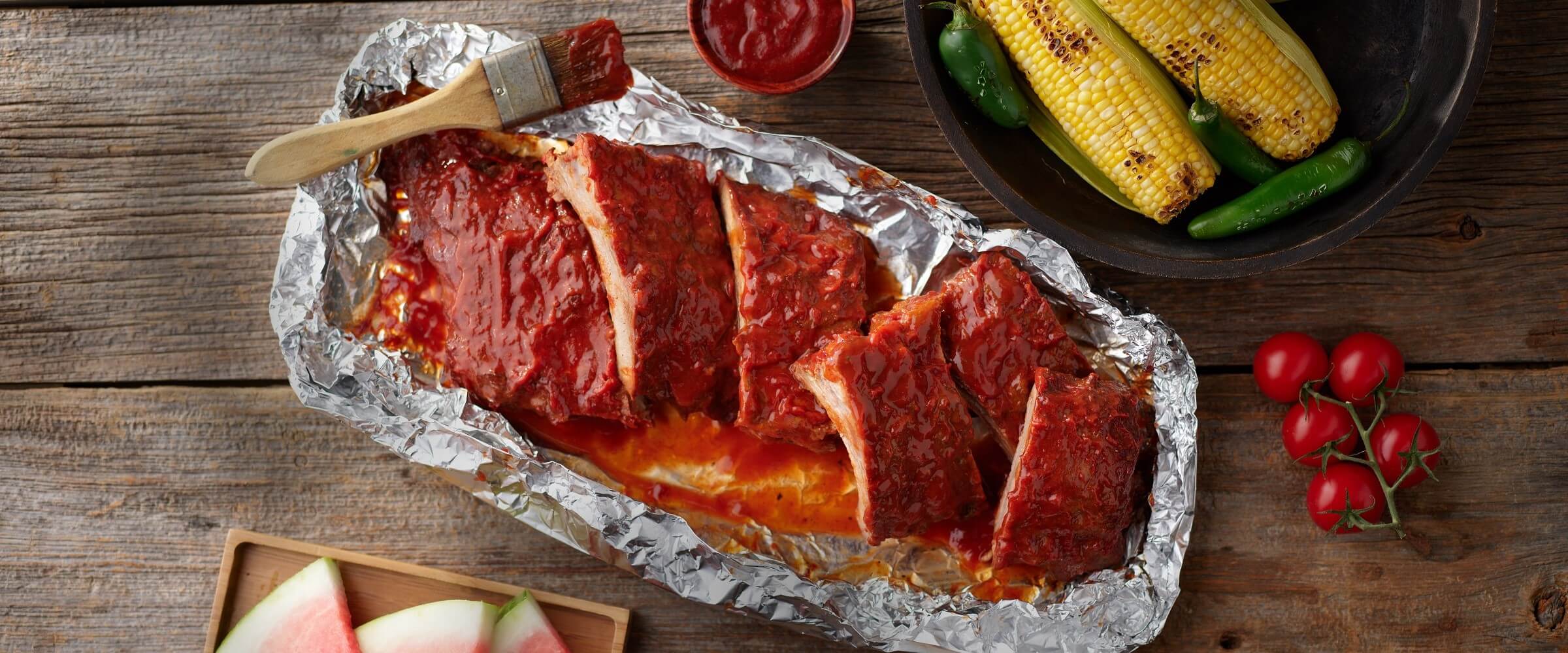 BBQ grilled babyback ribs in foil with extra sauce and sweet corn