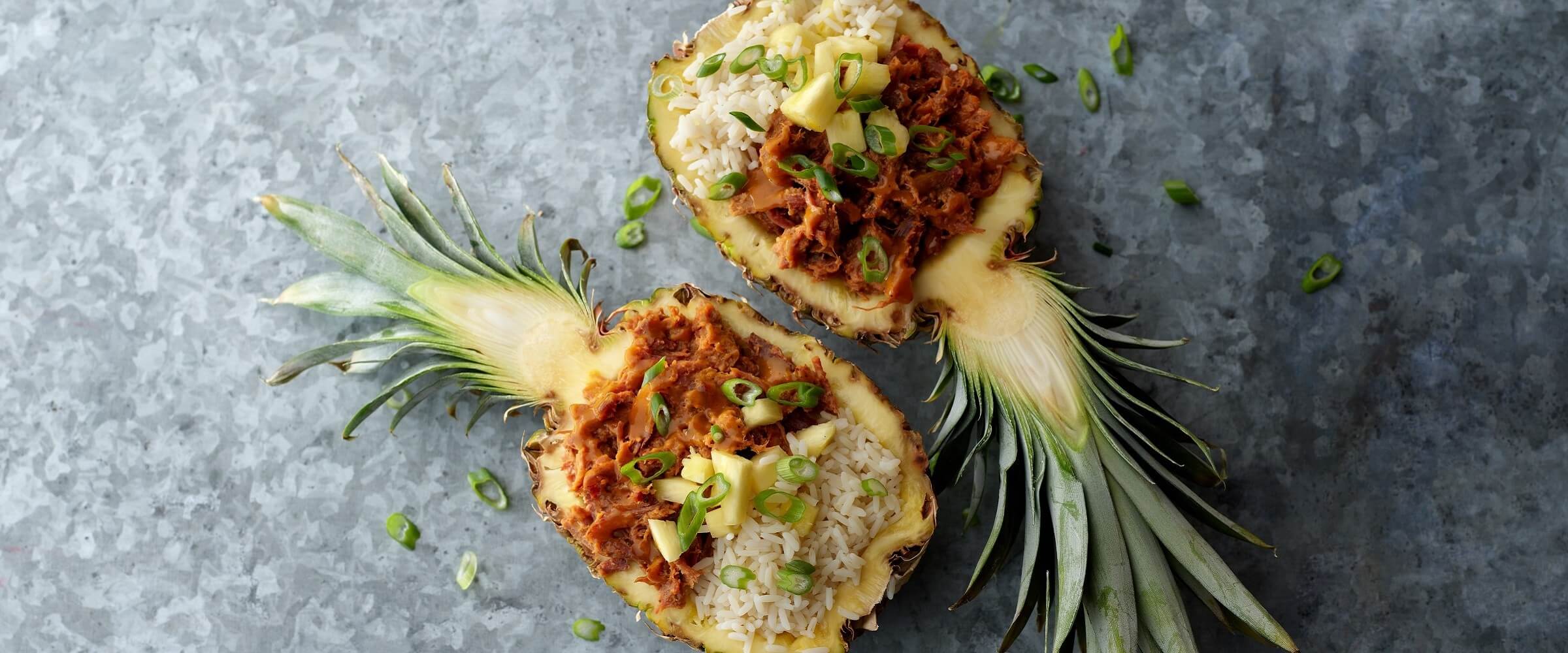 Rice Bowl in pineapple halves topped with green onions on gray platter