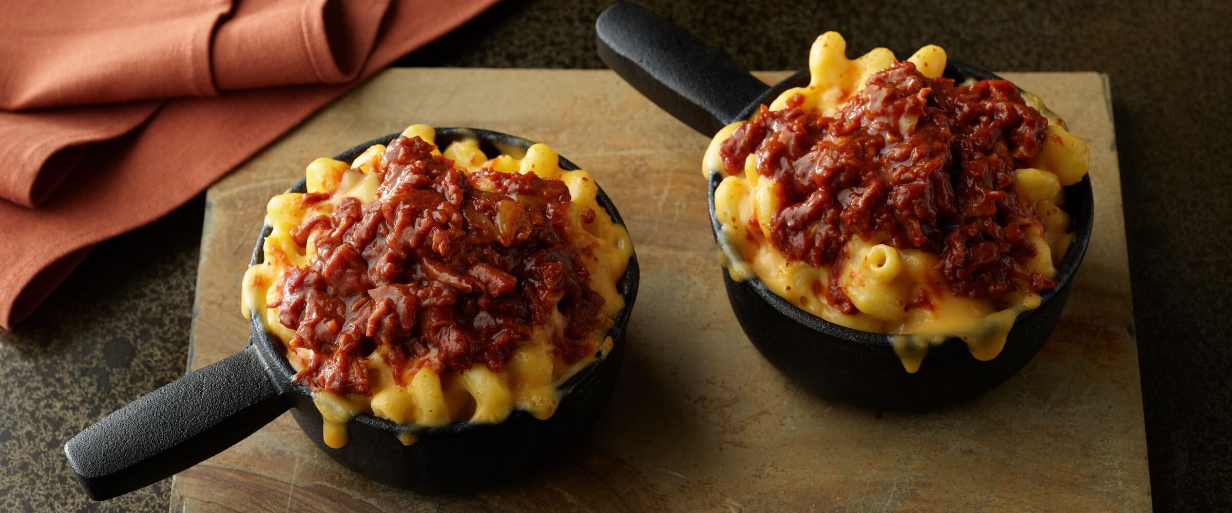 BBQ pulled pork mac and cheese in mini black skillet on a wood board