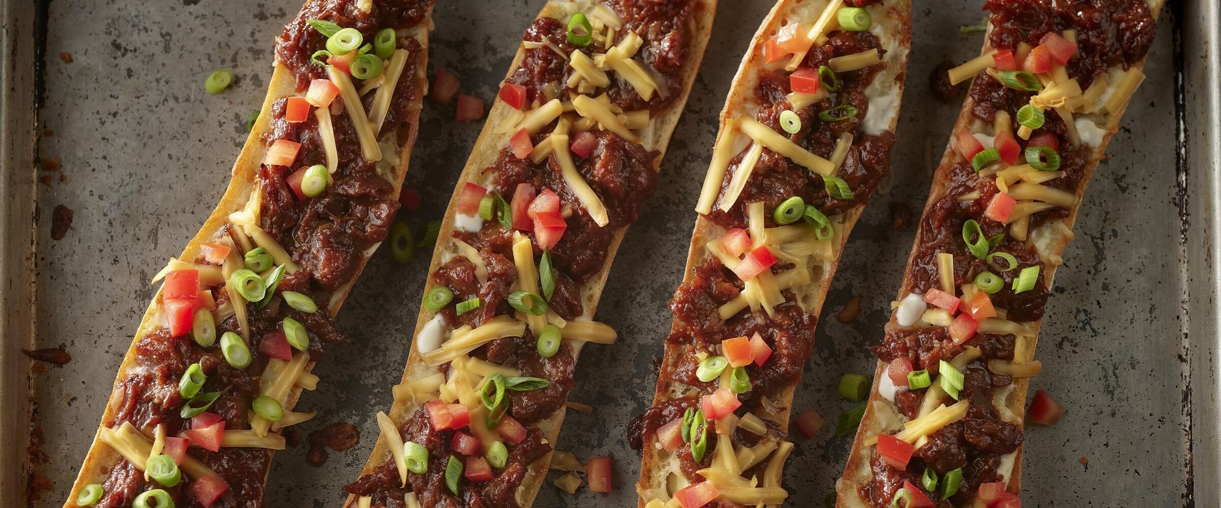 BBQ ranch baguette pizza topped with cheese, tomatoes and green onions on sheet pan