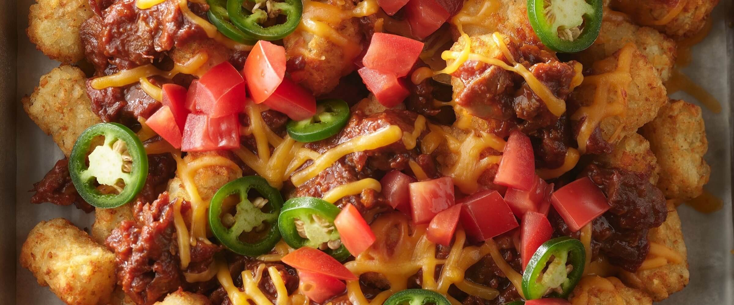 Loaded BBQ tachos topped with cheese, tomatoes and jalapenos