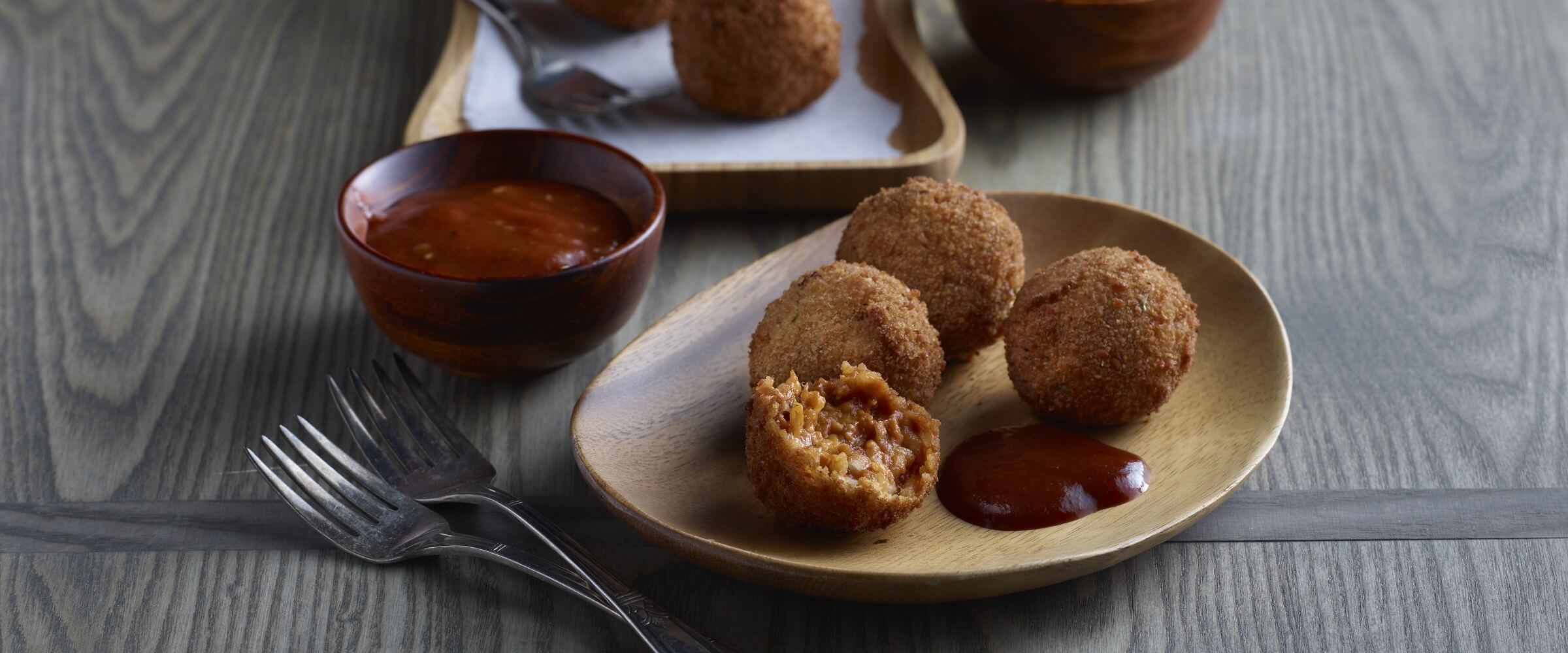 BBQ pulled pork arancini in wood bowl with dipping sauce and forks
