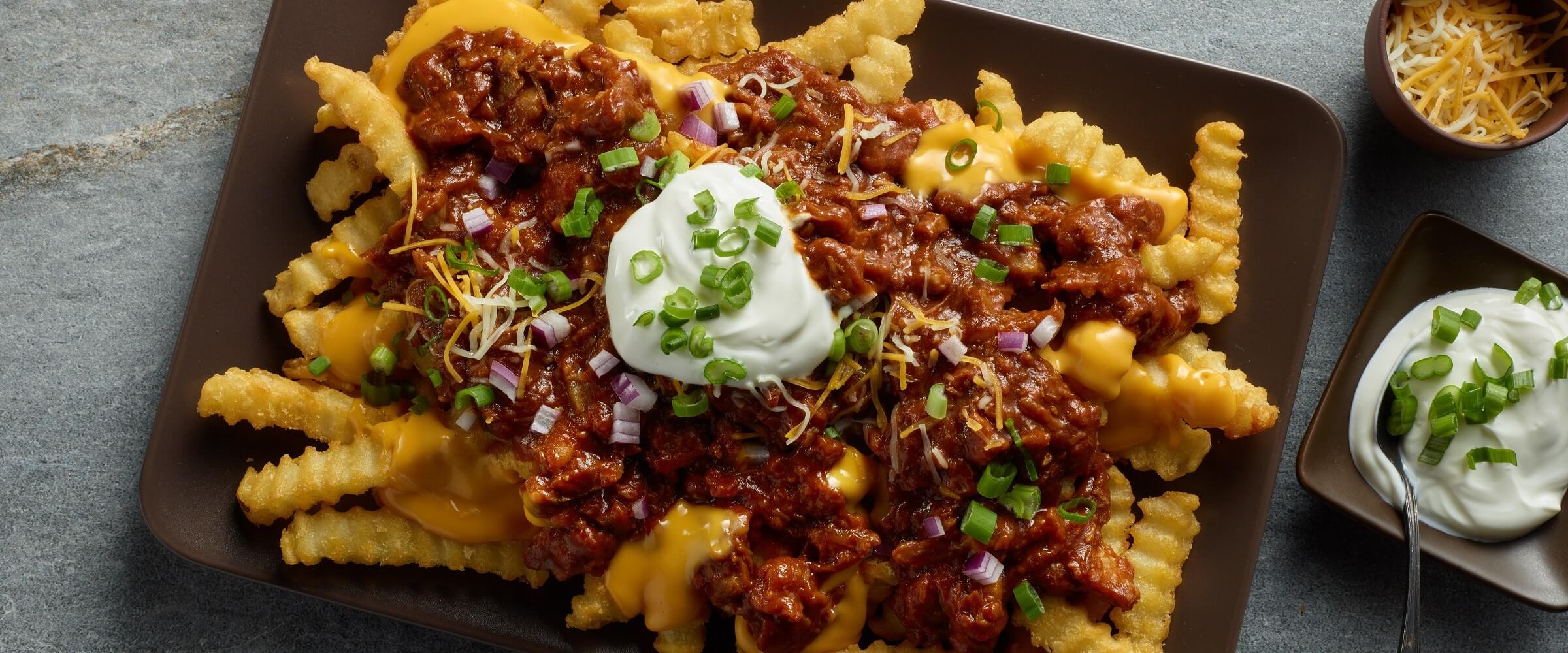 BBQ pulled pork loaded fries on plate plate topped with sour cream and green onions
