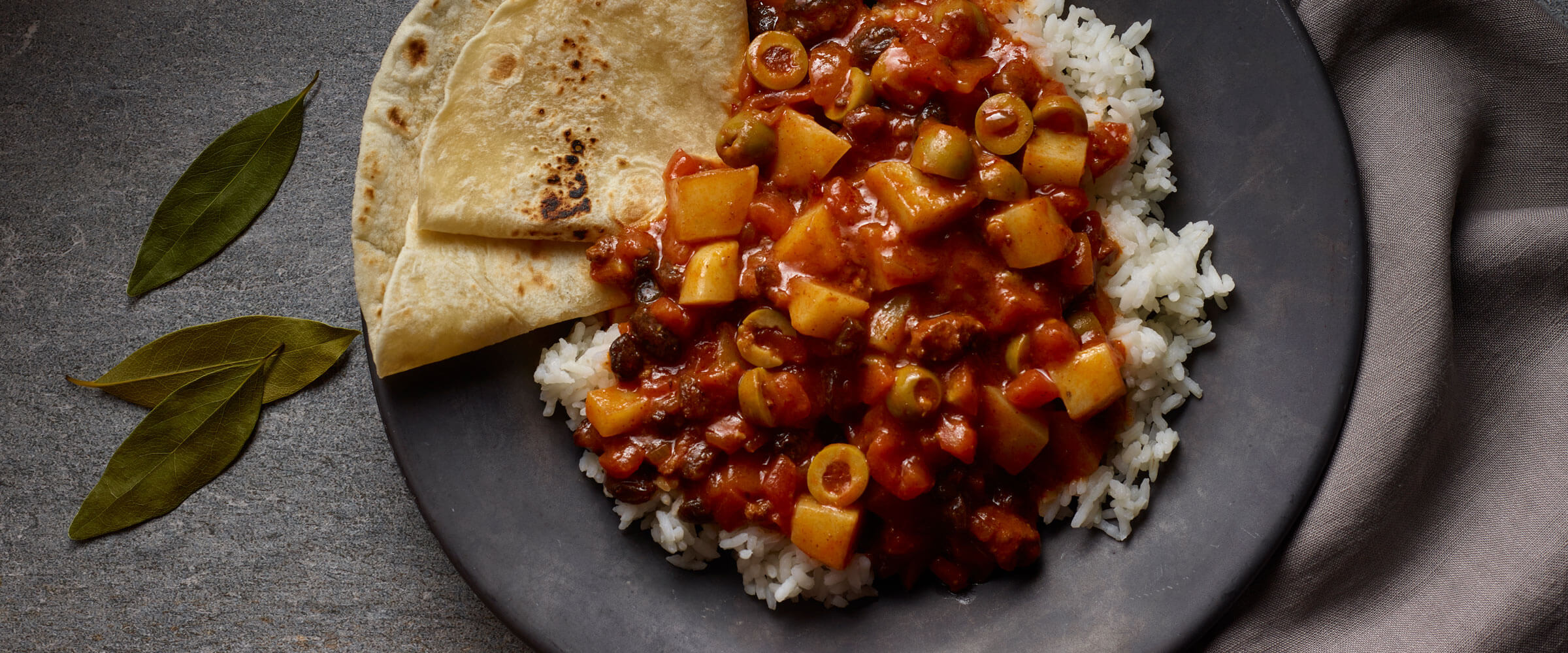 Chili Picadillo over rice with folded tortillas on gray plate