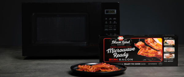 Microwave Ready Bacon package next to black microwave with bacon on plate