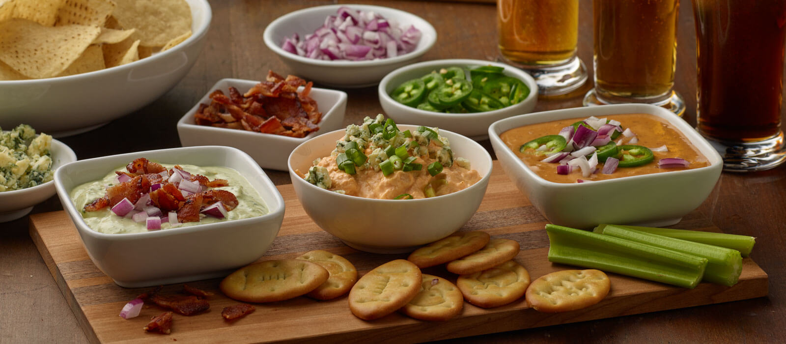 Spread of Game Day Dips on wood board with crackers and celery
