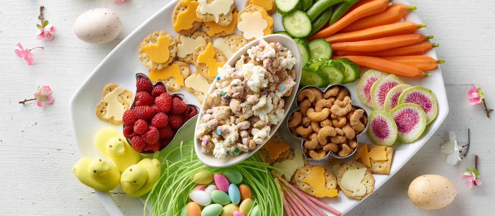 a spring themed snacking board with easter eggs and flowers
